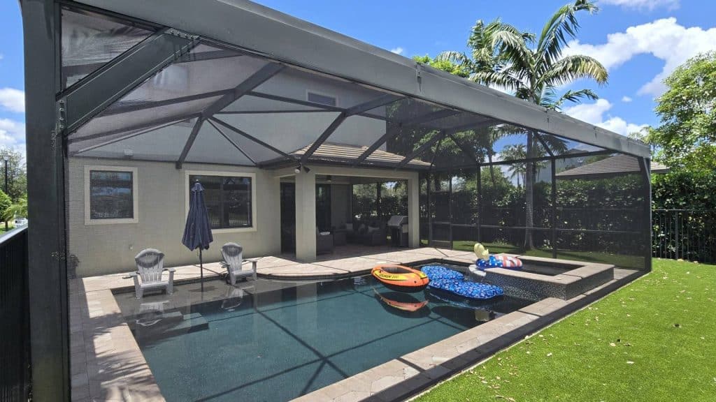 AAA Pro Screening photo of the back of a gray house with an enclosed swimming pool in Lake Worth FL