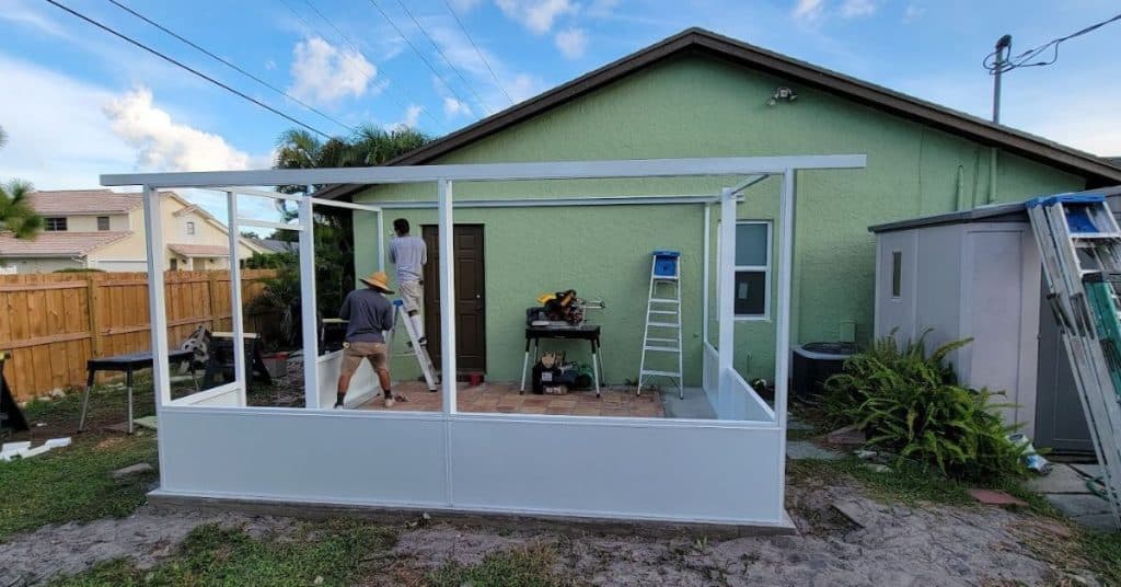 Professional installers assembling the aluminum frame for a screen room.